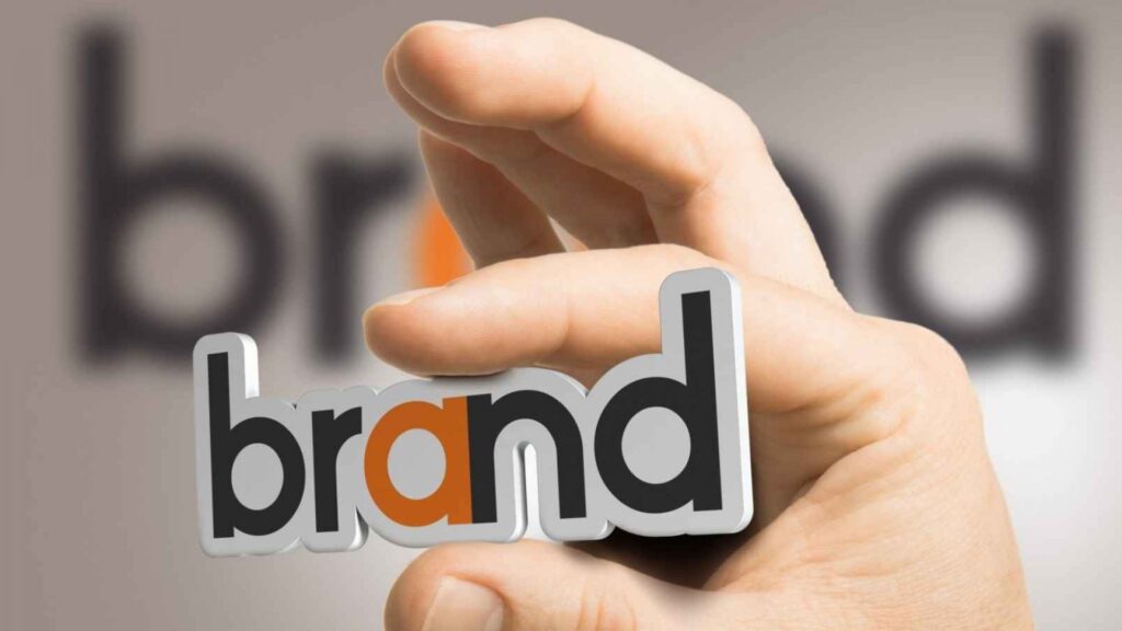 Photo d'une main tenant un magnet "Brand"